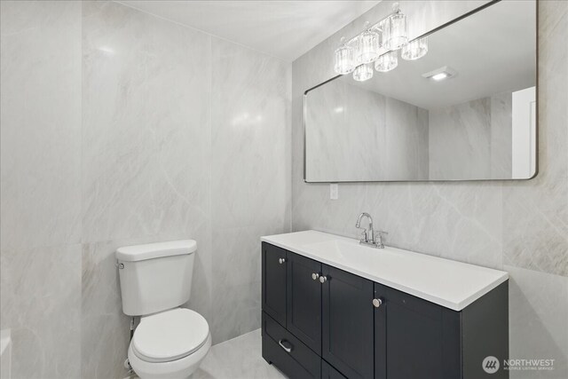 bathroom with tile walls, toilet, and vanity