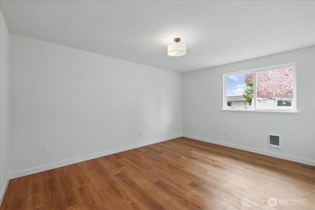 spare room featuring wood finished floors and baseboards