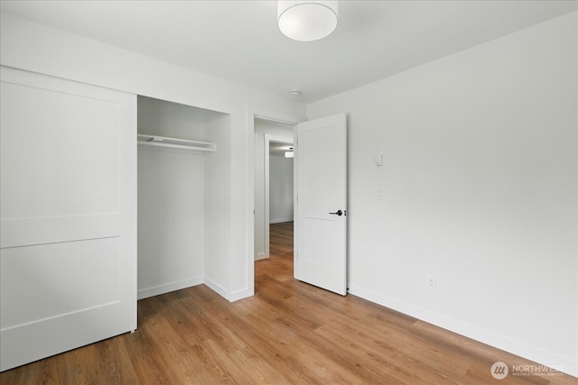 unfurnished bedroom with baseboards, a closet, and light wood-type flooring