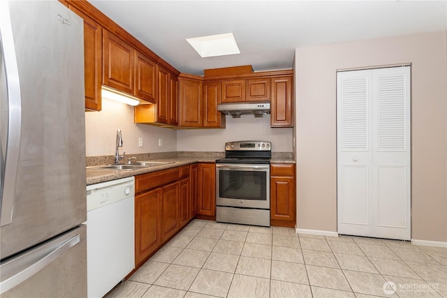 kitchen with under cabinet range hood, light tile patterned flooring, a sink, appliances with stainless steel finishes, and a skylight