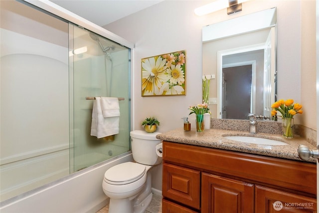 bathroom with toilet, vanity, and combined bath / shower with glass door