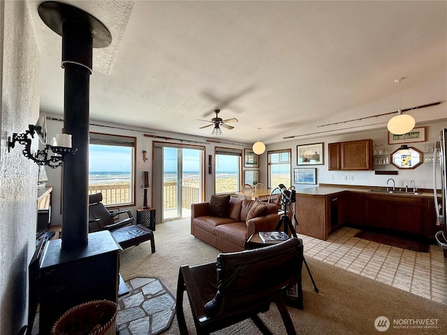 living area featuring a wood stove, light colored carpet, and a ceiling fan