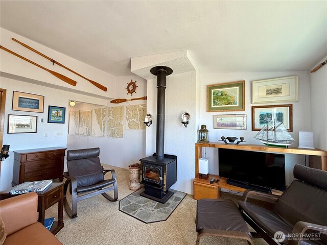 carpeted living room featuring vaulted ceiling and a wood stove