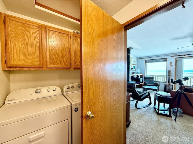 laundry room featuring light colored carpet, cabinet space, and washer and dryer