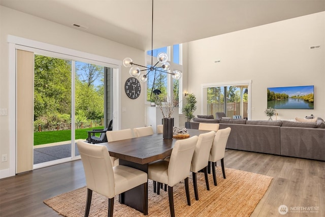 8650 NE Reserve Way, Bainbridge Island, WA 98110 - dining room featuring wood finished floors, a chandelier, and a high ceiling