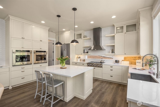 8650 NE Reserve Way, Bainbridge Island, WA 98110 - kitchen with wall chimney exhaust hood, appliances with stainless steel finishes, open shelves, a center island, and dark wood finished floors