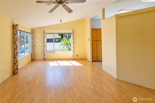 empty room with lofted ceiling, light wood-style floors, and ceiling fan