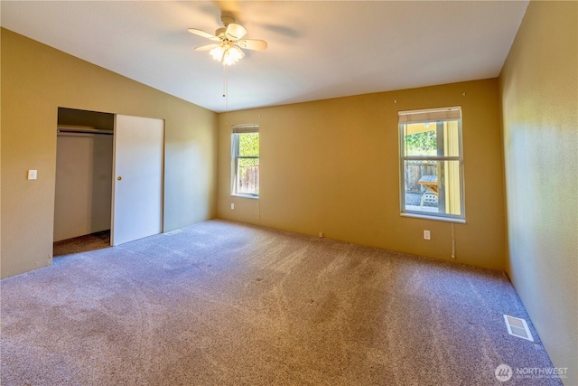 unfurnished bedroom featuring carpet flooring, a ceiling fan, a closet, visible vents, and lofted ceiling