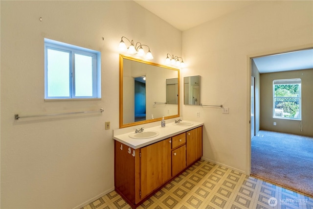 bathroom featuring baseboards, double vanity, and a sink