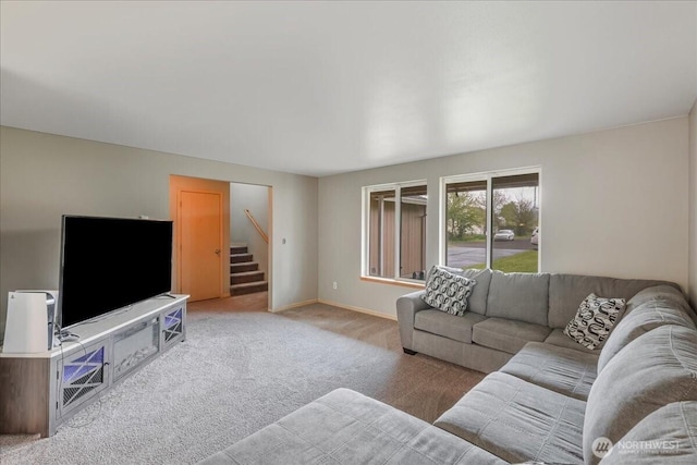 living room featuring baseboards, light carpet, and stairway