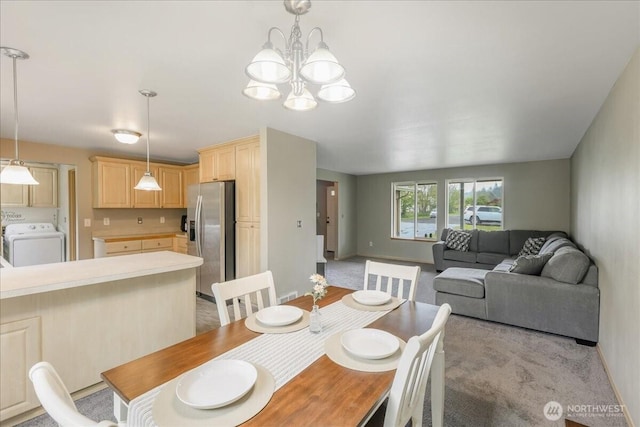 dining space with an inviting chandelier, light carpet, baseboards, and washer / clothes dryer