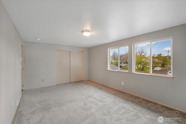 unfurnished bedroom featuring light colored carpet, a closet, and baseboards