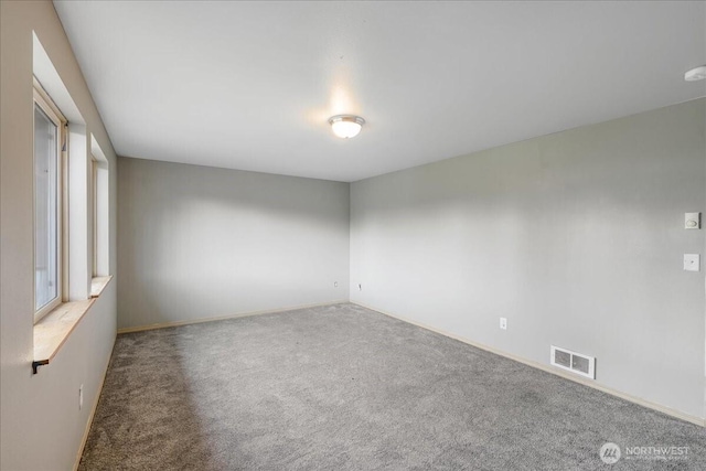 carpeted spare room featuring baseboards and visible vents