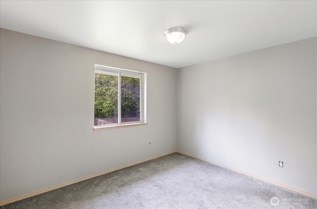 unfurnished room featuring carpet and baseboards