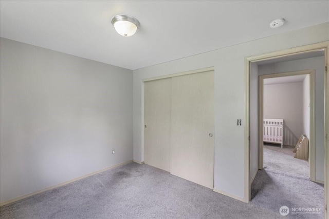 unfurnished bedroom with baseboards, carpet flooring, and a closet