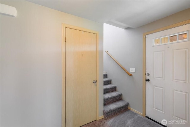 carpeted foyer featuring baseboards and stairway