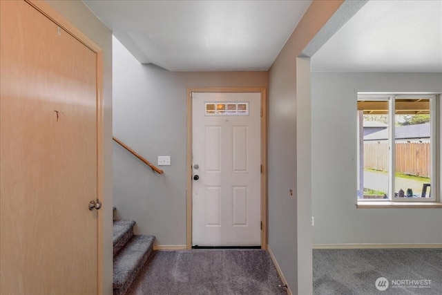 carpeted foyer with stairs and baseboards