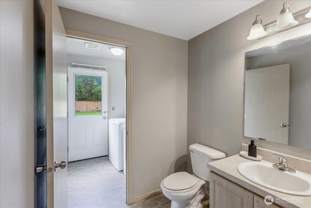 half bathroom featuring toilet, washer / clothes dryer, and vanity