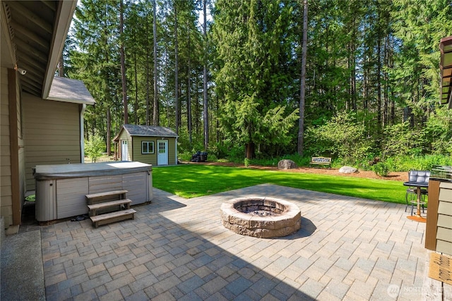 view of patio featuring an outdoor fire pit, an outbuilding, and a hot tub