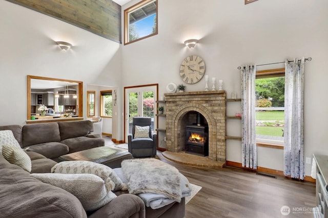 living area with a towering ceiling, baseboards, plenty of natural light, and wood finished floors