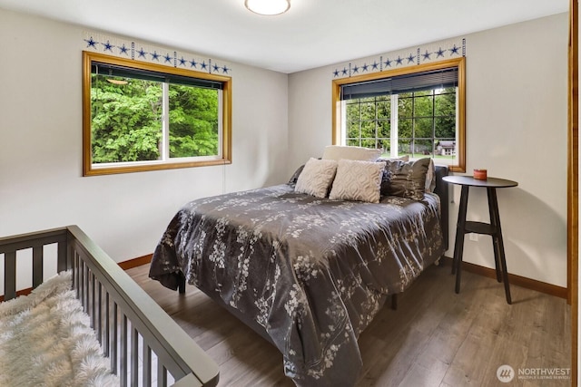 bedroom featuring multiple windows, wood finished floors, and baseboards
