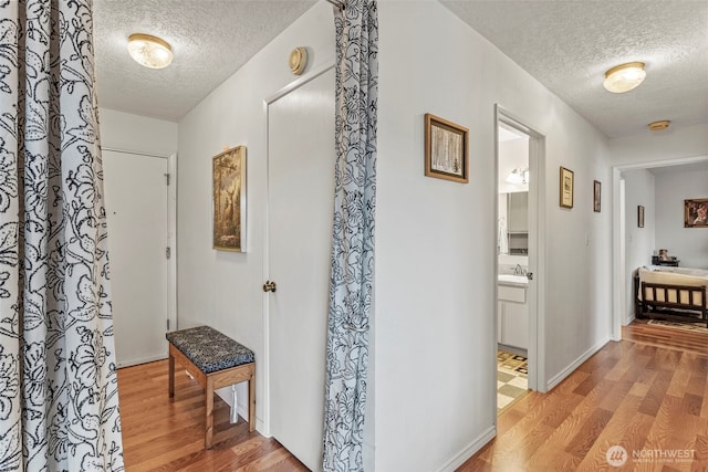 hall with light wood finished floors and a textured ceiling