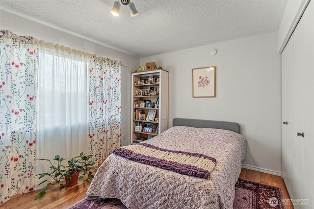 bedroom featuring a textured ceiling, a closet, and wood finished floors