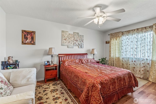 bedroom with a textured ceiling, wood finished floors, and a ceiling fan