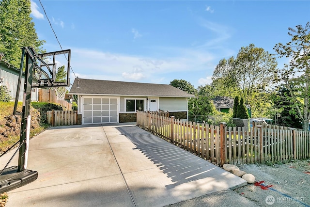 view of front facade with driveway, an attached garage, fence private yard, and stone siding