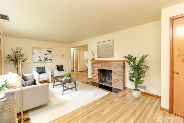 living area featuring a fireplace, baseboards, visible vents, and wood finished floors