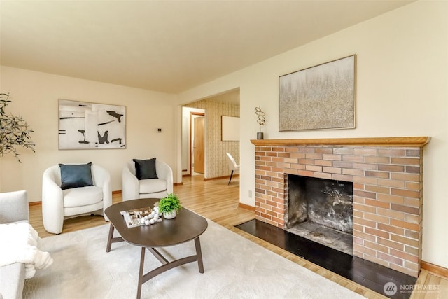 living area featuring a fireplace, baseboards, and wood finished floors