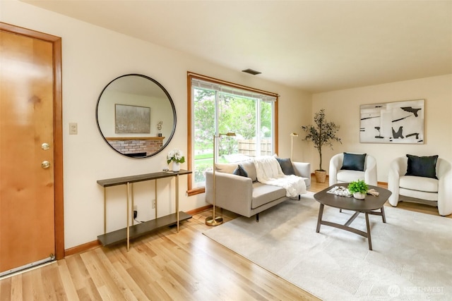 living room featuring light wood-style floors, visible vents, and baseboards