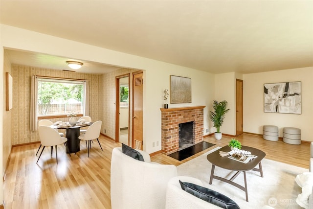 living room featuring baseboards, a fireplace, and light wood-style flooring