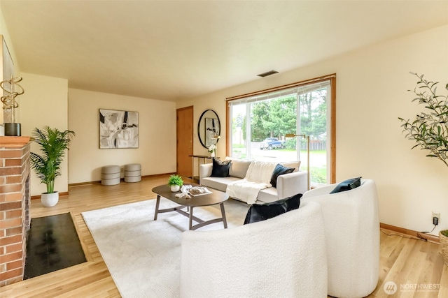 living room with baseboards, visible vents, and wood finished floors