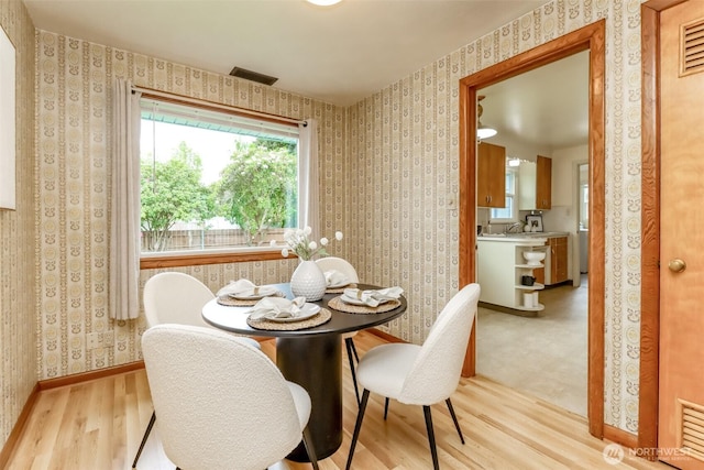 dining room featuring visible vents, light wood-style flooring, and wallpapered walls