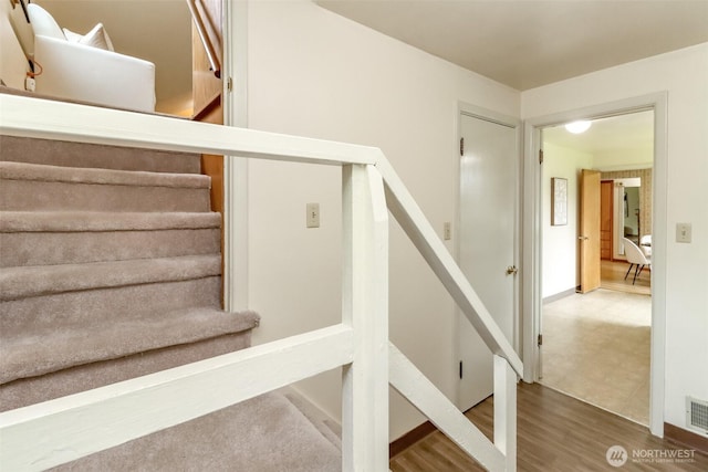 stairway featuring visible vents and wood finished floors
