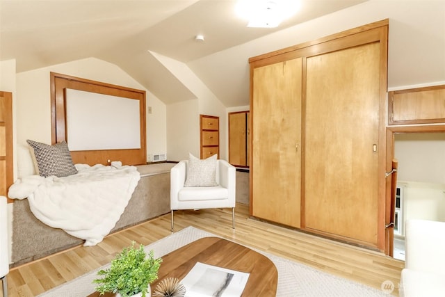 bedroom with a closet, visible vents, light wood-style flooring, and lofted ceiling