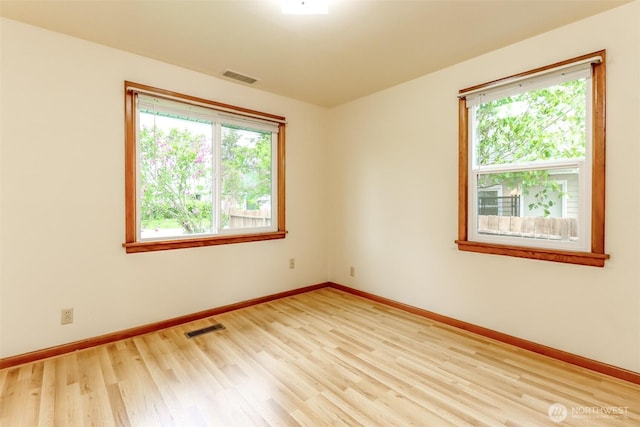 empty room featuring light wood-style flooring, baseboards, and visible vents