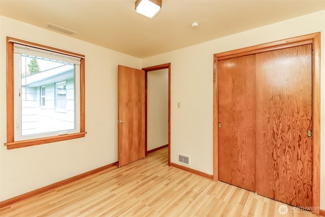 unfurnished bedroom with a closet, visible vents, light wood-style flooring, and baseboards