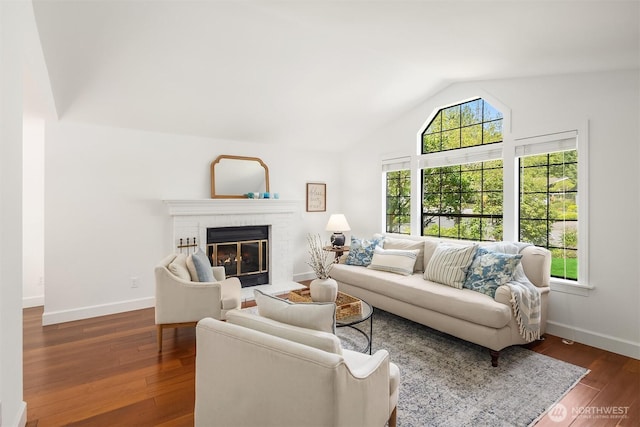 living room featuring lofted ceiling, baseboards, a fireplace, and dark wood-style flooring