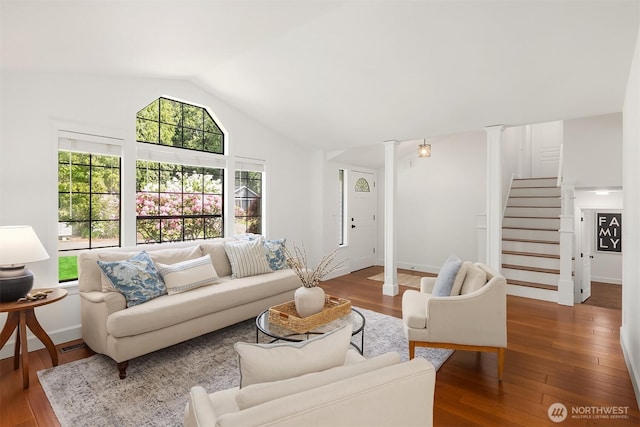 living area with decorative columns, lofted ceiling, hardwood / wood-style floors, and stairs