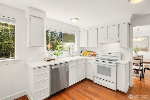 kitchen featuring electric range, stainless steel dishwasher, a sink, under cabinet range hood, and plenty of natural light