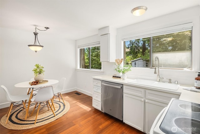 kitchen with stainless steel dishwasher, a sink, wood finished floors, and white cabinetry