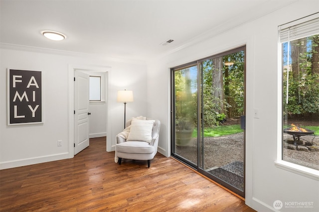 living area with ornamental molding, wood finished floors, and baseboards
