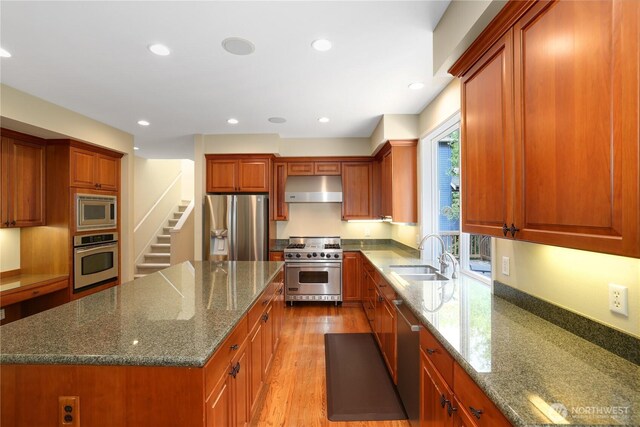 25846 NE 4th Pl, Sammamish, WA 98074 - kitchen featuring appliances with stainless steel finishes, a sink, under cabinet range hood, dark stone counters, and a center island