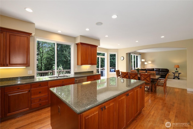 25846 NE 4th Pl, Sammamish, WA 98074 - kitchen featuring a sink, a center island, dark stone countertops, arched walkways, and light wood-style floors