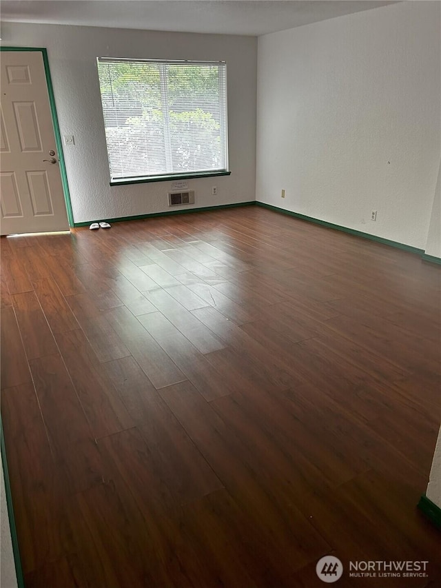 spare room featuring dark wood-style floors and baseboards