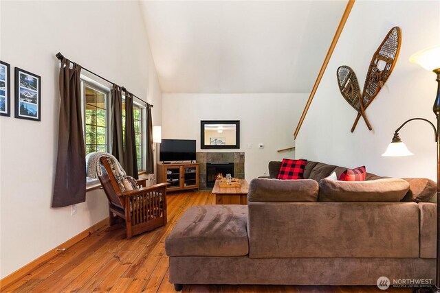 12026 Shuksan Rim Dr, Deming, WA 98244 - living area featuring hardwood / wood-style floors, a tiled fireplace, high vaulted ceiling, and baseboards