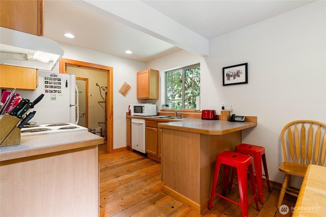 12026 Shuksan Rim Dr, Deming, WA 98244 - kitchen featuring white appliances, under cabinet range hood, light wood-type flooring, a peninsula, and a kitchen breakfast bar