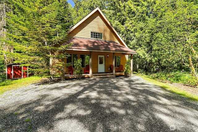 12026 Shuksan Rim Dr, Deming, WA 98244 - rustic home with a porch, a shed, an outbuilding, a view of trees, and a shingled roof